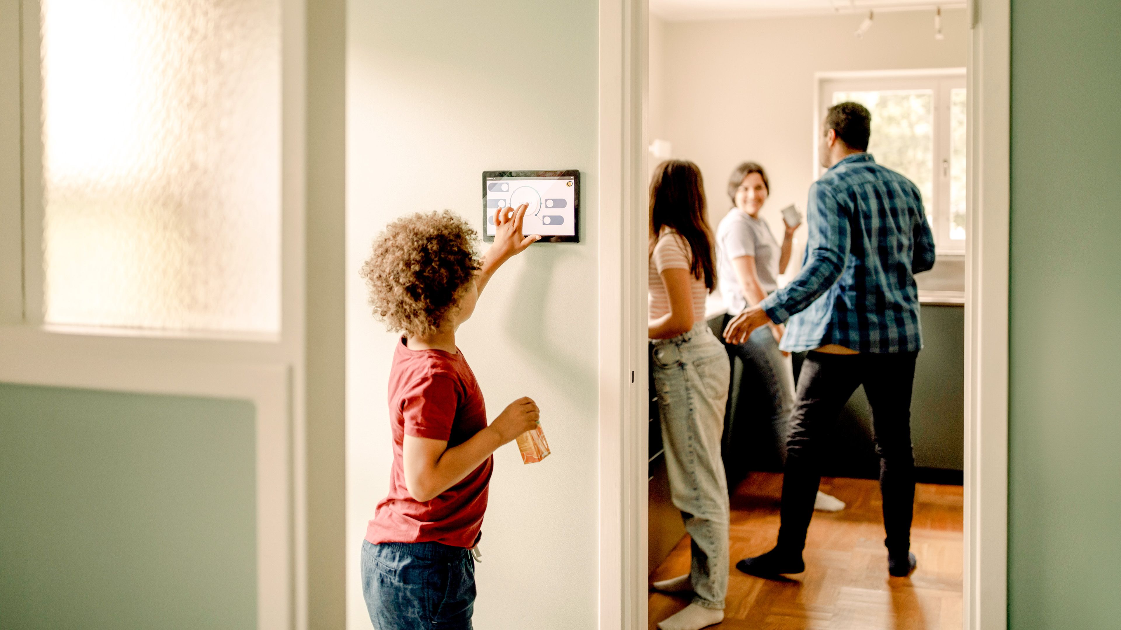 Kind tippt auf Touchscreen zur Regelung von Strom, mehrere Personen sind im Hintergrund
