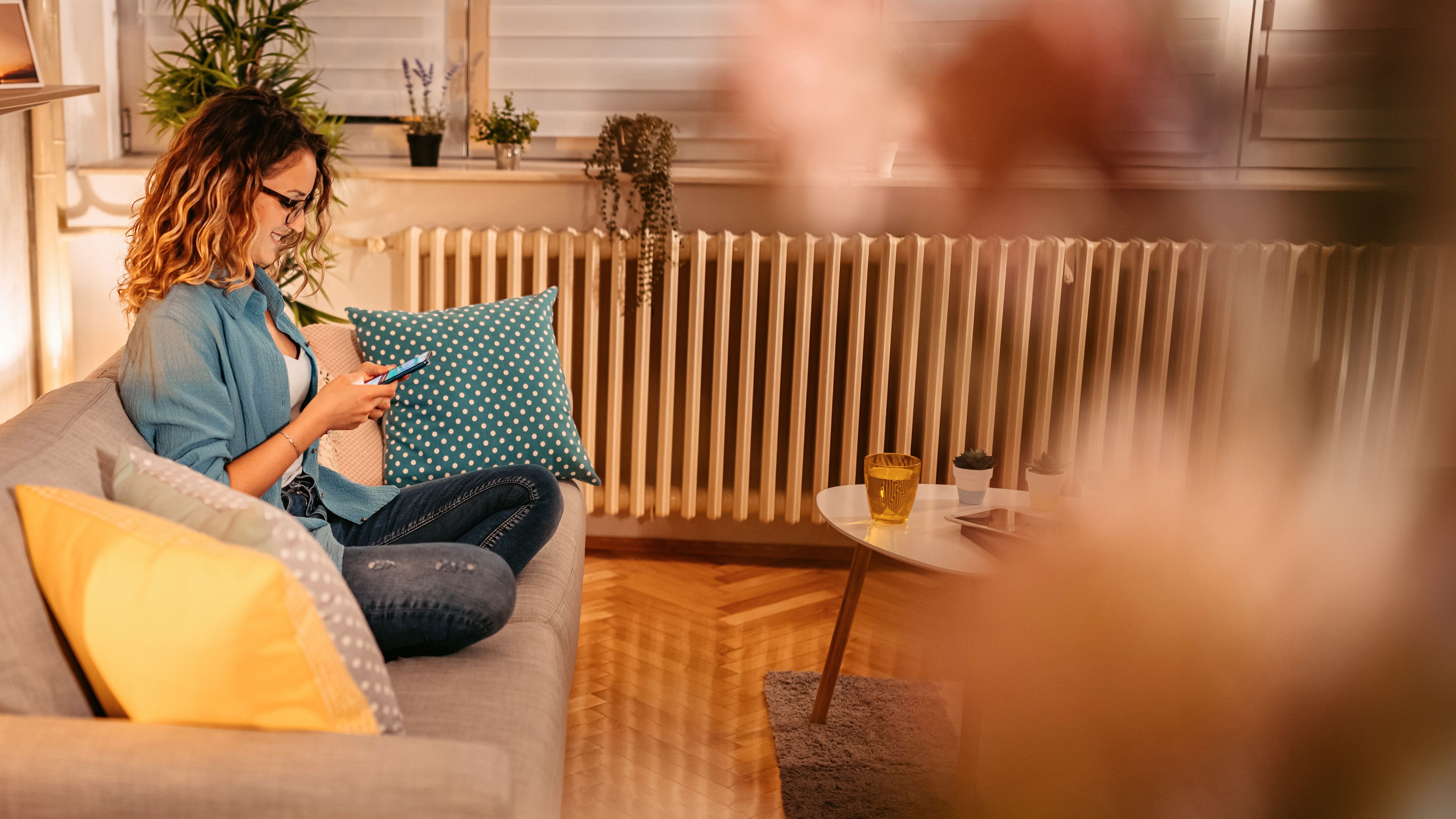 Frau sitzt am Handy auf dem Sofa