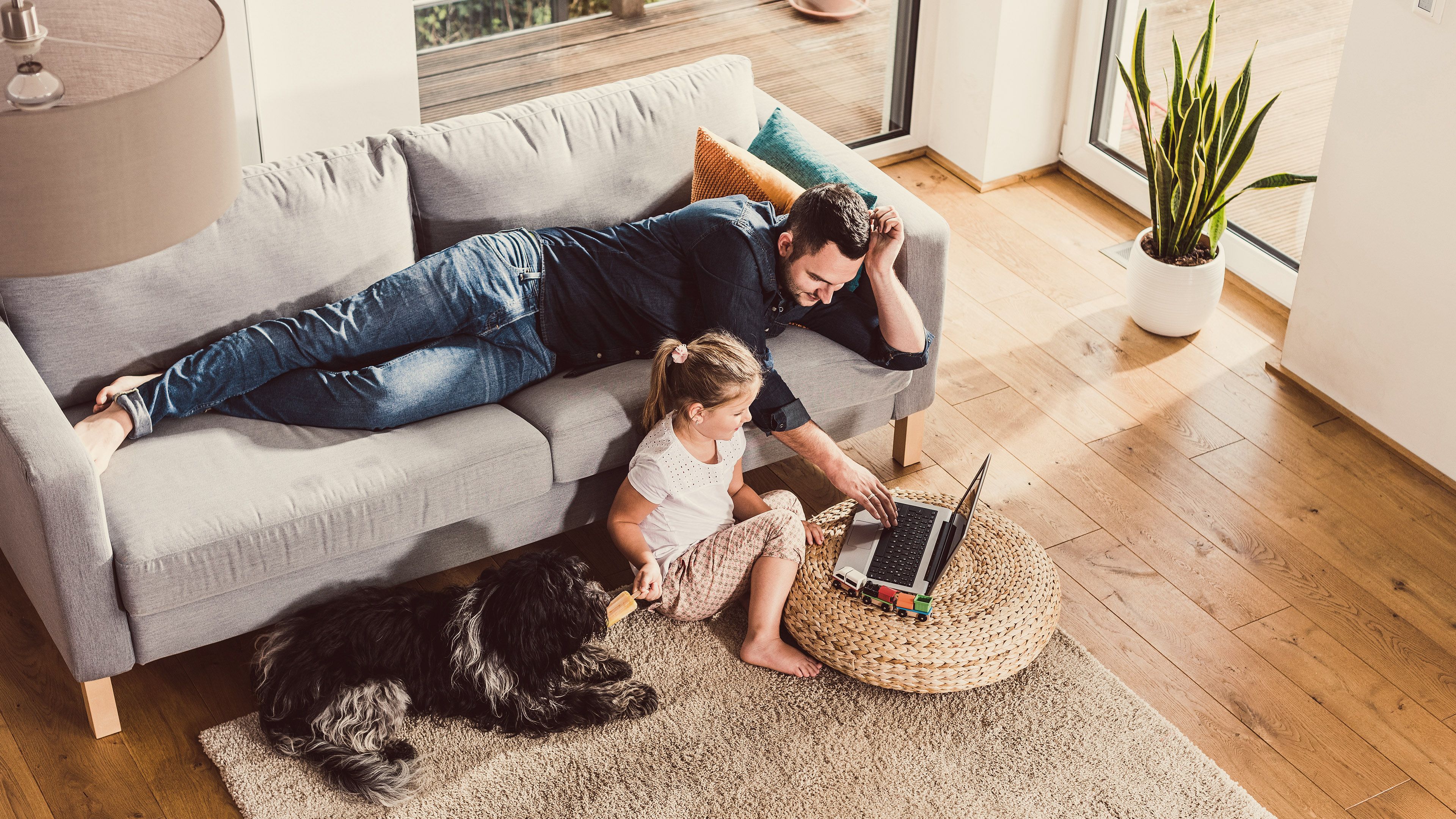 Mann mit Kind und Hund vor dem Laptop