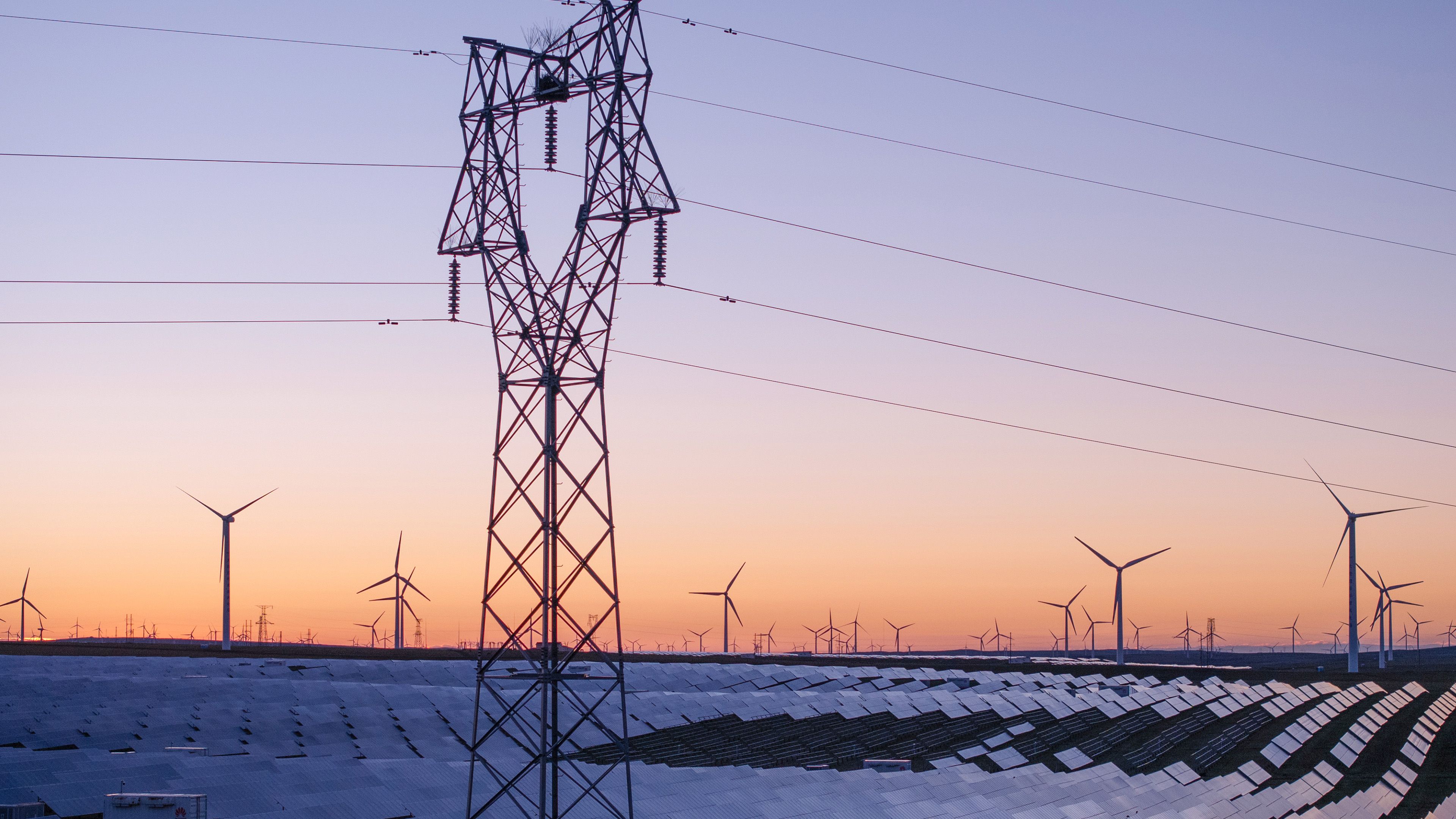 Solarpark mit Windraedern und Stromleitungen im Hintergrund