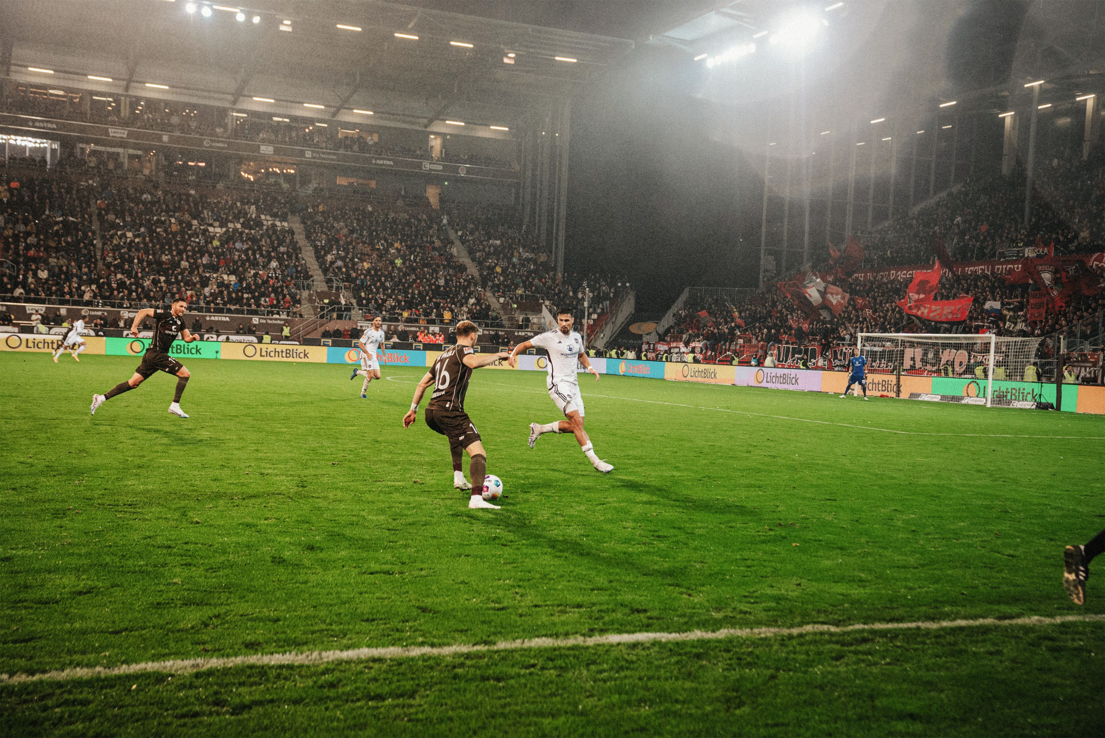 Fußballspieler des FC St. Pauli spielen im Stadion vor LichtBlick Bannerwerbung