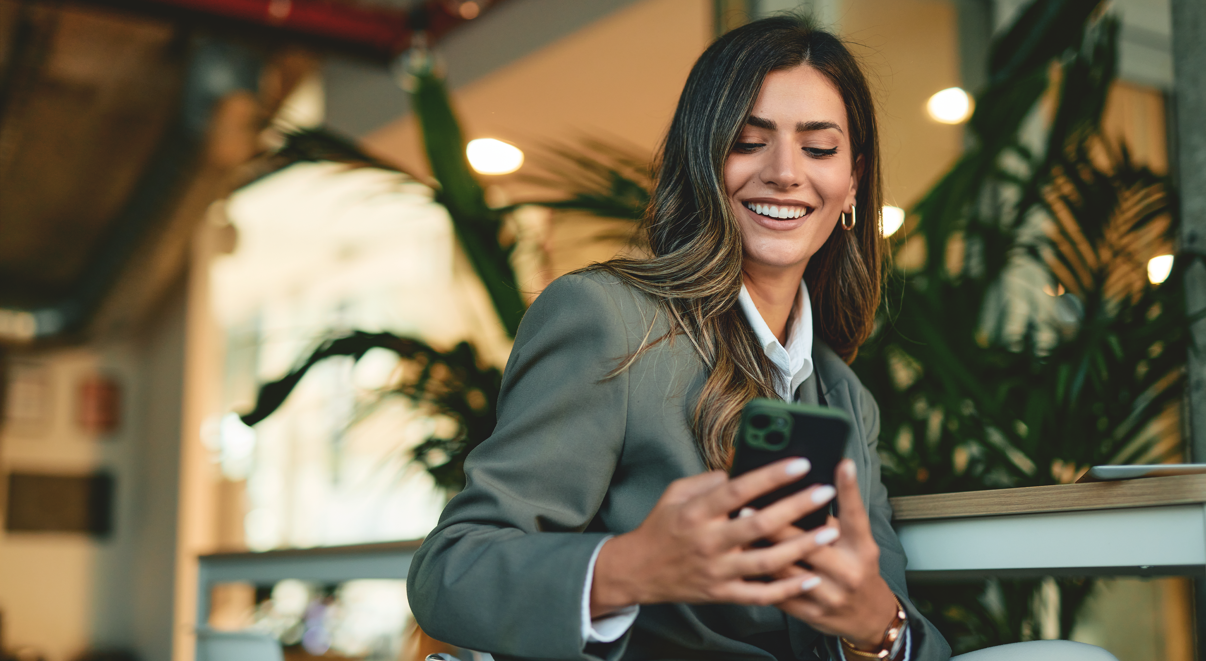 Frau in Blazer schaut auf ihr Handy