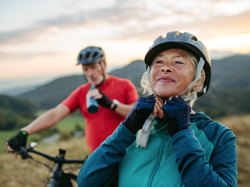 Eine Frau macht sich den Fahrradhelm zu