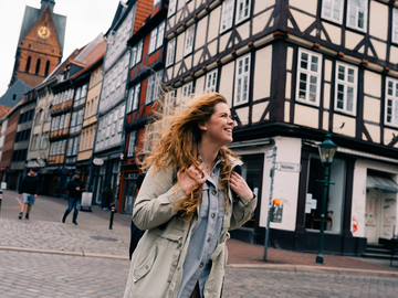 Frau mit Rucksack in Stadt vor Fachwerkhaus