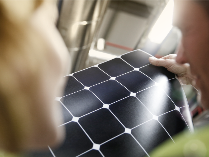 Eine undeutlich zu erkennende Person hält eine Matte aus Dünnschicht-Solarzellen in den Händen.