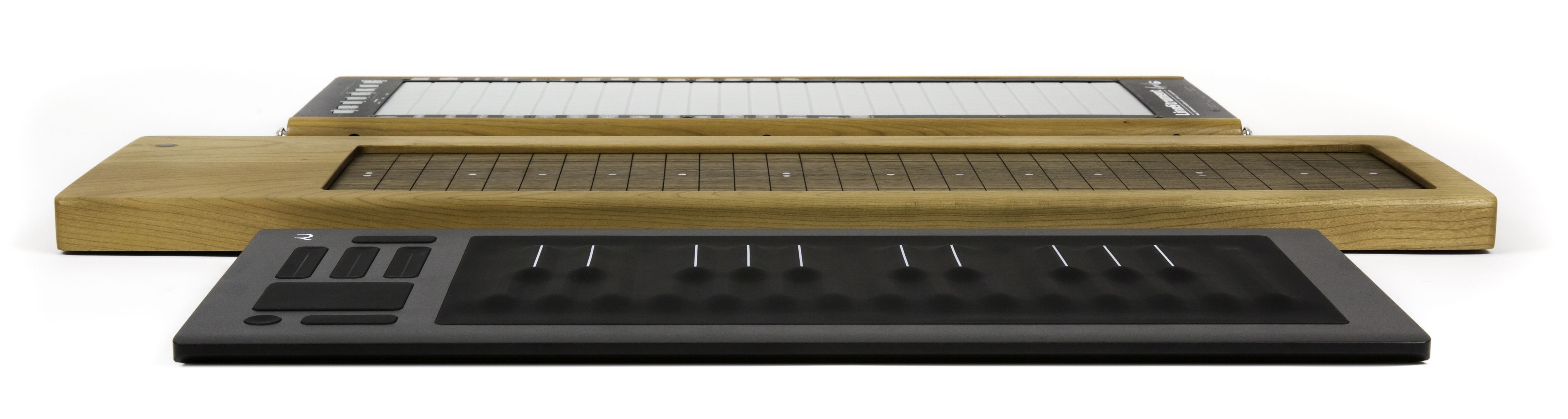 Three electronic musical instruments with touch-sensitive surfaces, varying in size and color, arranged in a row on a white background.