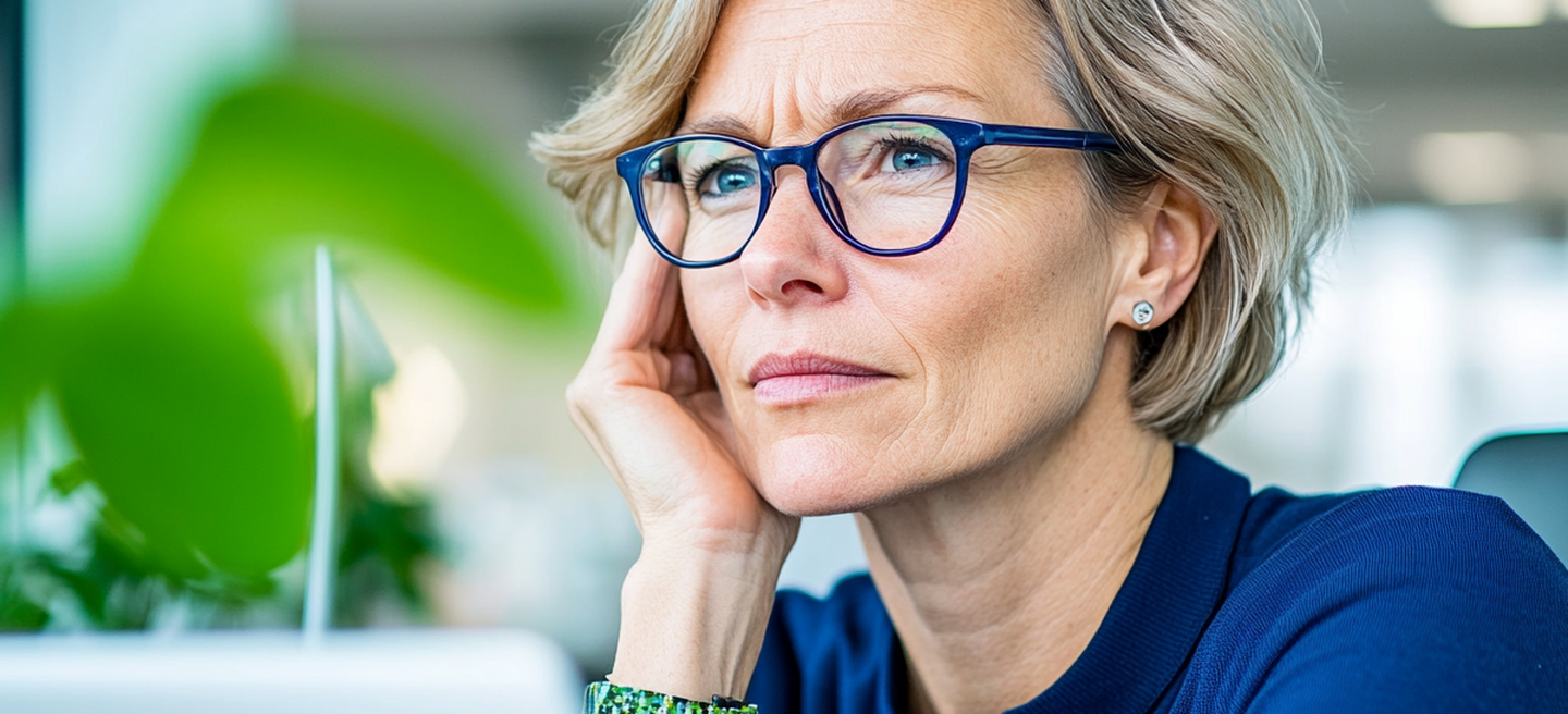 Femme d’affaires avec des lunettes concentrée sur l’écran de son ordinateur portable dans un bureau lumineux avec des plantes