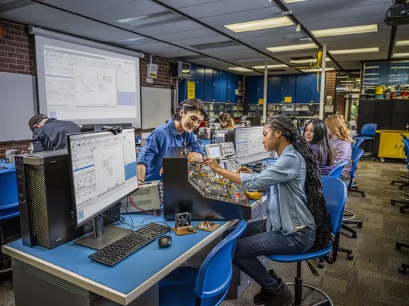 Engineering team members in a factory setting use Autodesk software during onboarding and upskilling activities, adapting their technical expertise to modern digital tools