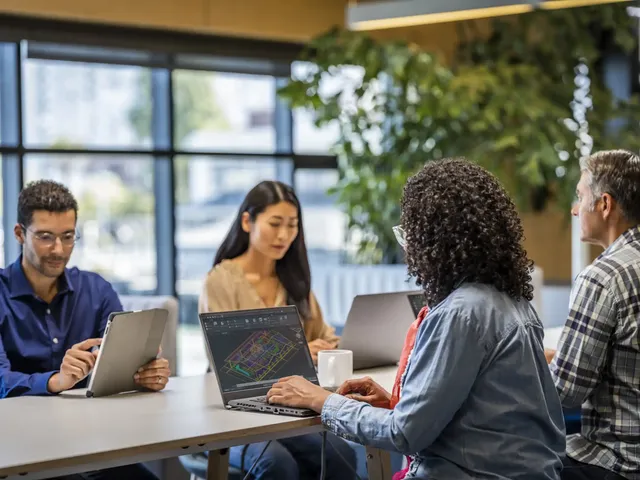 A diverse team of professionals participates in an onboarding session while working with Autodesk software, collaborating around shared screens and discussing design workflows in a modern office