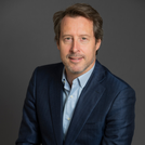 Philippe Monnoyeur, posing against a gray background with a slight smile.