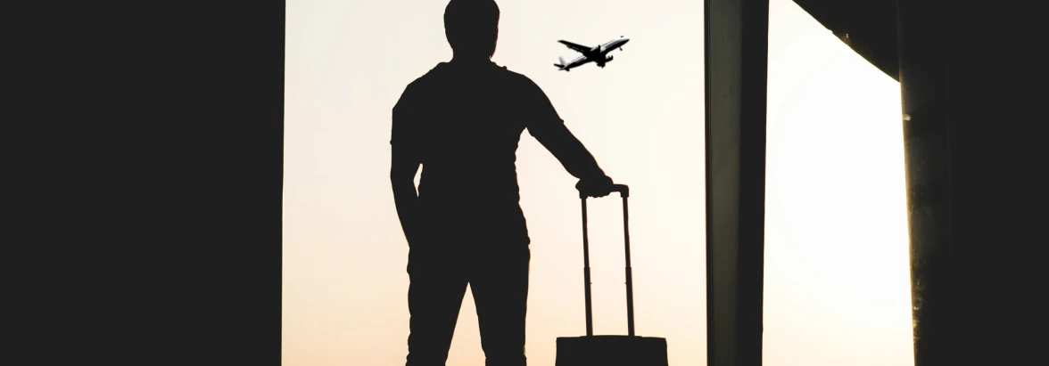 Enterprise connectivity - male traveler looking out at a plane taking off