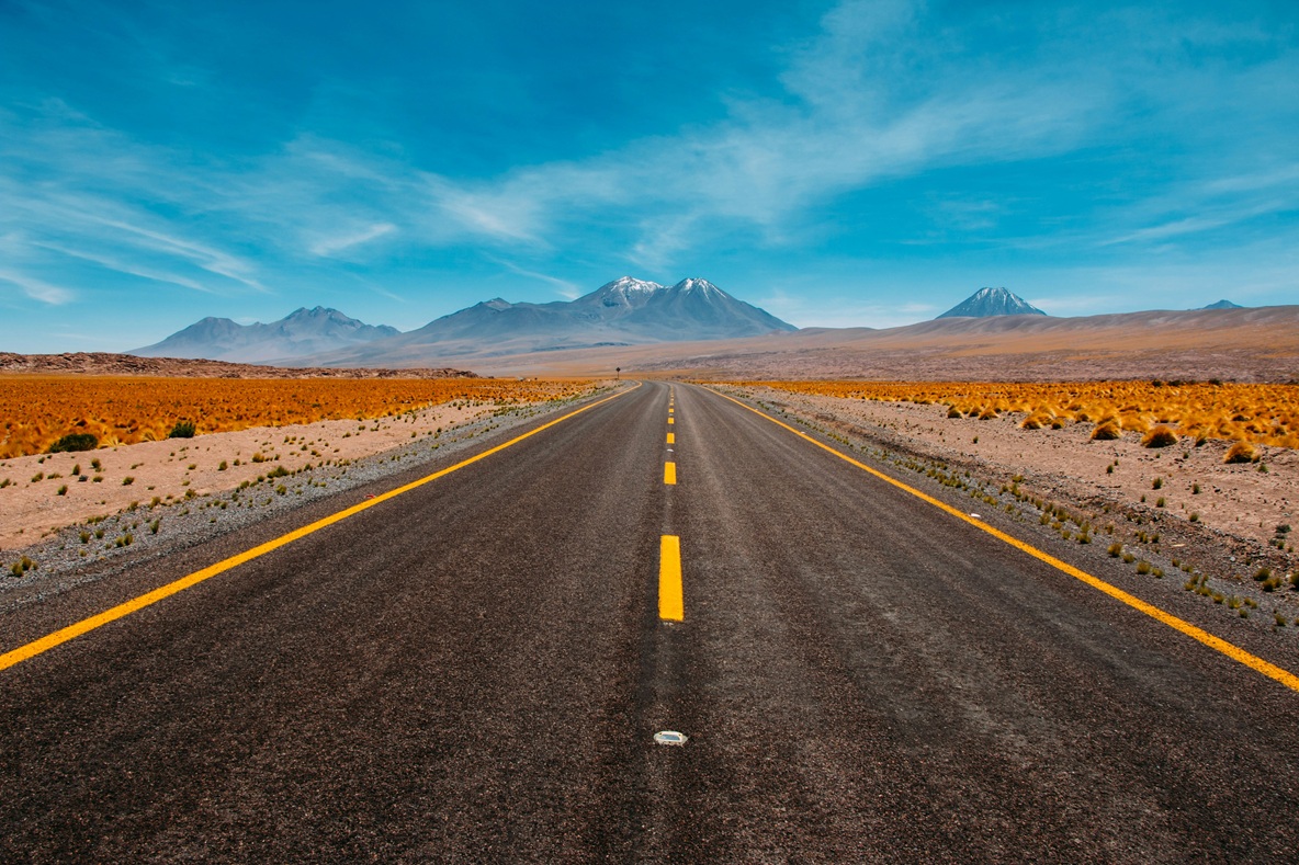 Road ahead through a desert landscape with mountainous backdrop