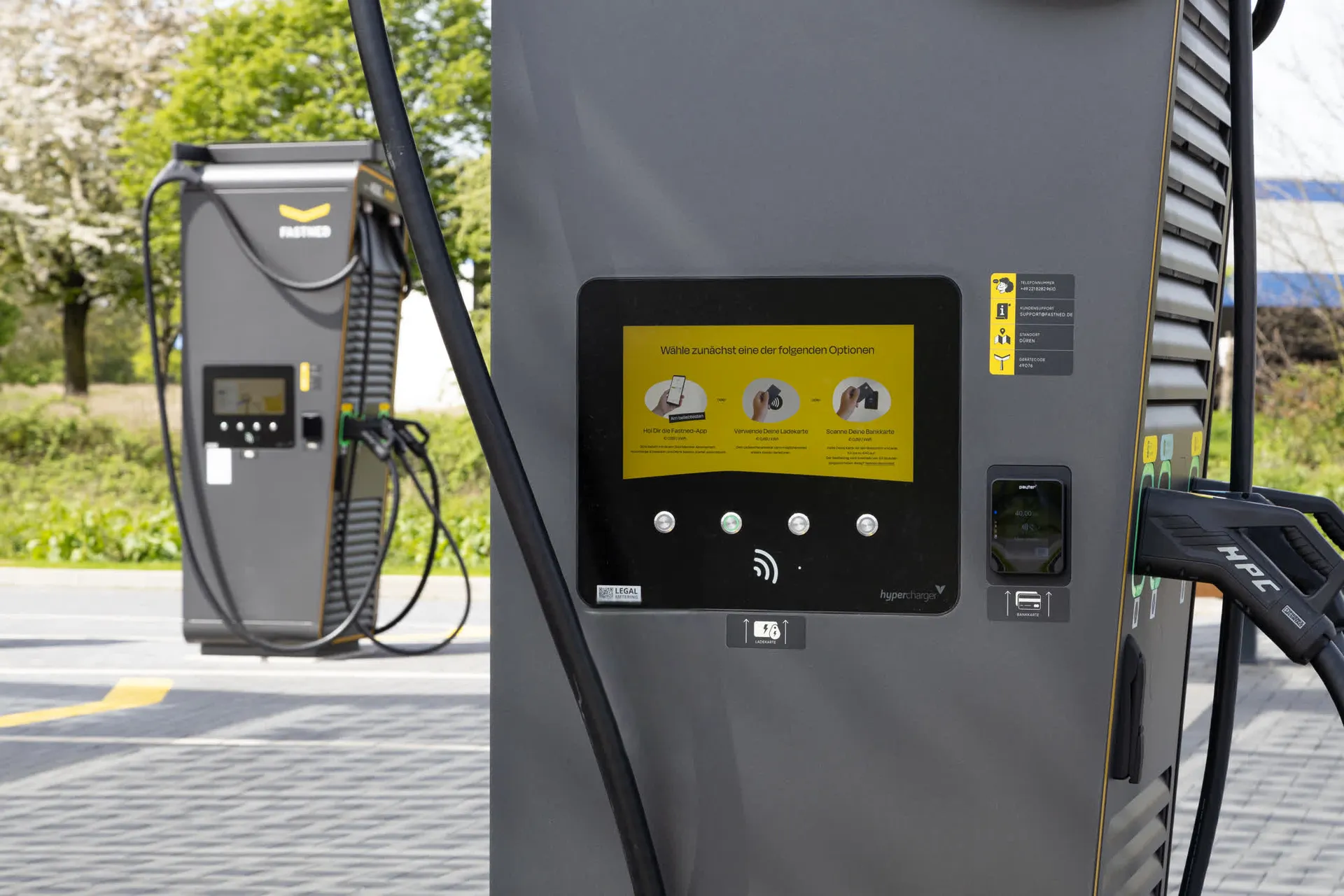 Nahaufnahme einer grauen Schnellladesäule für Elektroautos. Das Display zeigt eine bebilderte Anleitung zum Ladevorgang. Unter dem Bildschirm ist Aufkleber des Deutschlandnetz zu sehen.