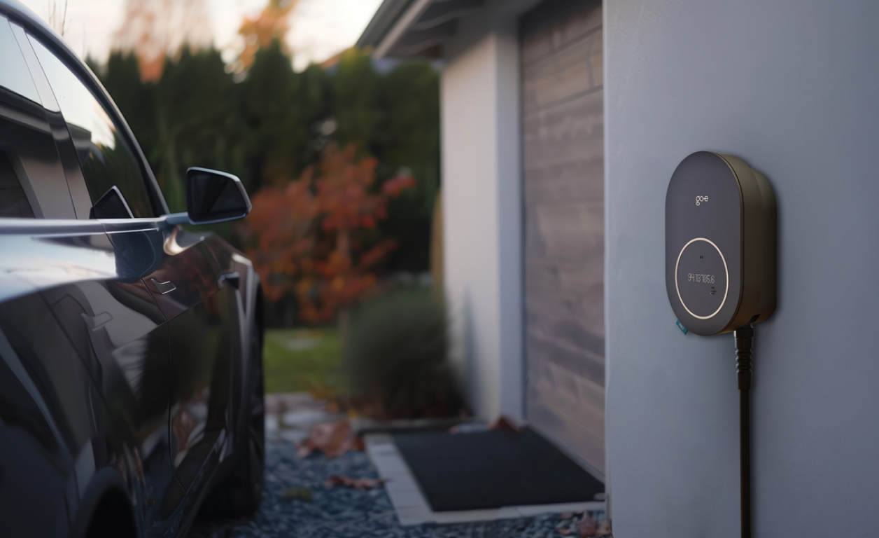 Eine schwarze Wallbox lädt ein Auto neben einer Garage