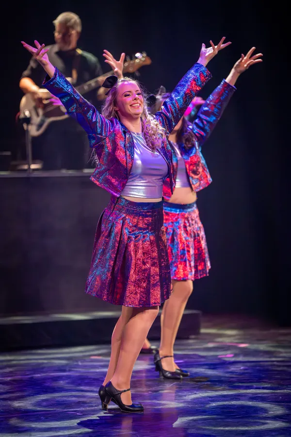 Twee dansers in paarse glitterkostuums met de armen omhoog
