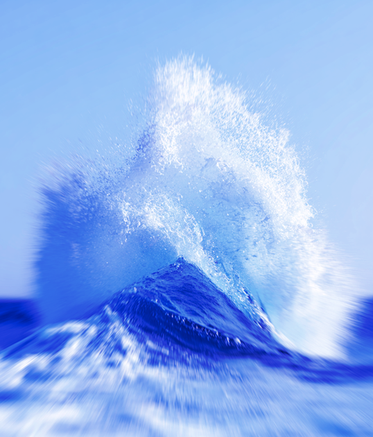 Woman in a black top and bright yellow pants stands confidently against a clear blue sky, wearing sunglasses and hoop earrings.