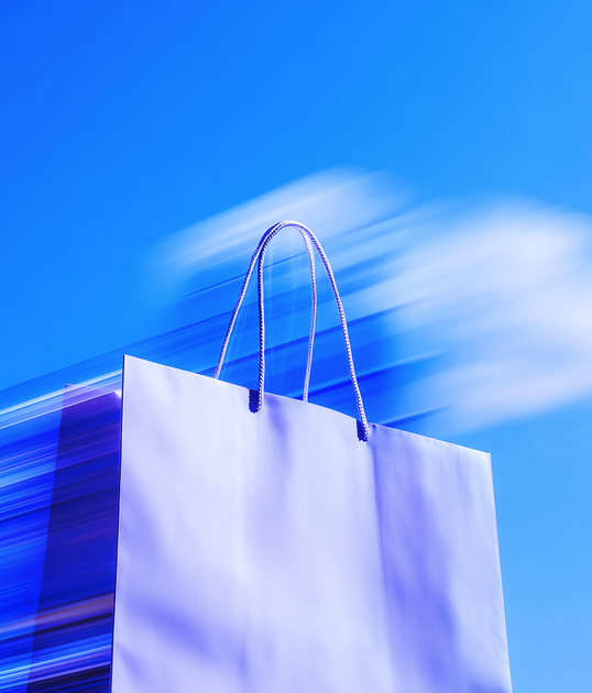 Young man in a red cap and shirt takes a selfie outdoors, with buildings and a bus in the blurred background under a clear blue sky.