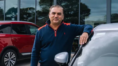 Rideshare driver standing with car in car yard