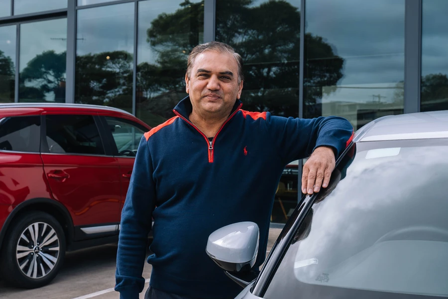 Rideshare driver standing with car in car yard