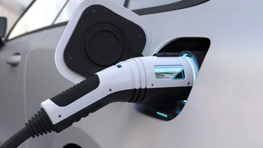 Close-up of an electric car charging with a plugged-in EV charger showing a full battery indicator.