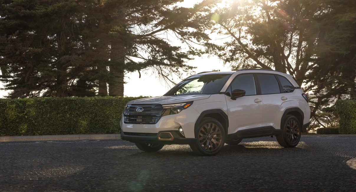 White Subaru Hybrid  SUV parked on a cobblestone road, surrounded by trees and hedges, with sunlight filtering through the branches.