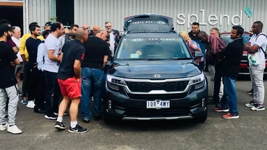 A group of people surrounding a Kia Vehicle in front of the Melbourne Splend hub