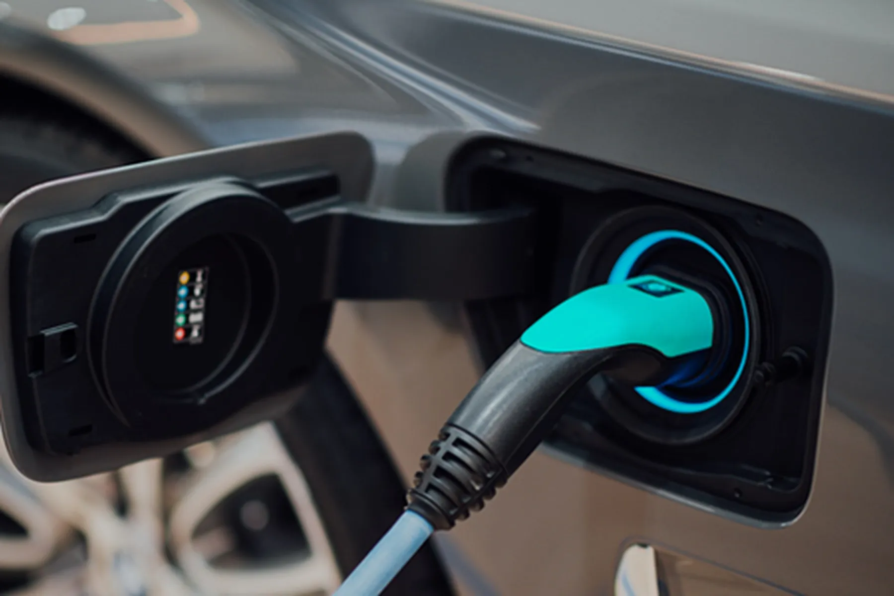 Close-up of an electric vehicle charging with a cable plugged into the front port