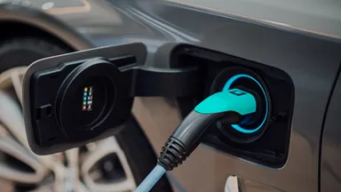 Close-up of an electric vehicle charging with a cable plugged into the front port