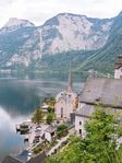 Blick auf die malerische Stadt Hallstatt am Ufer eines ruhigen Sees, umgeben von hohen Bergen und üppiger Natur.