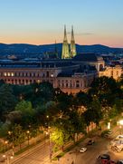 Abendstimmung in Wien mit Blick auf die beleuchtete Votivkirche, das Rathaus und die historische Ringstraße – eine beeindruckende Kulisse in der Dämmerung.