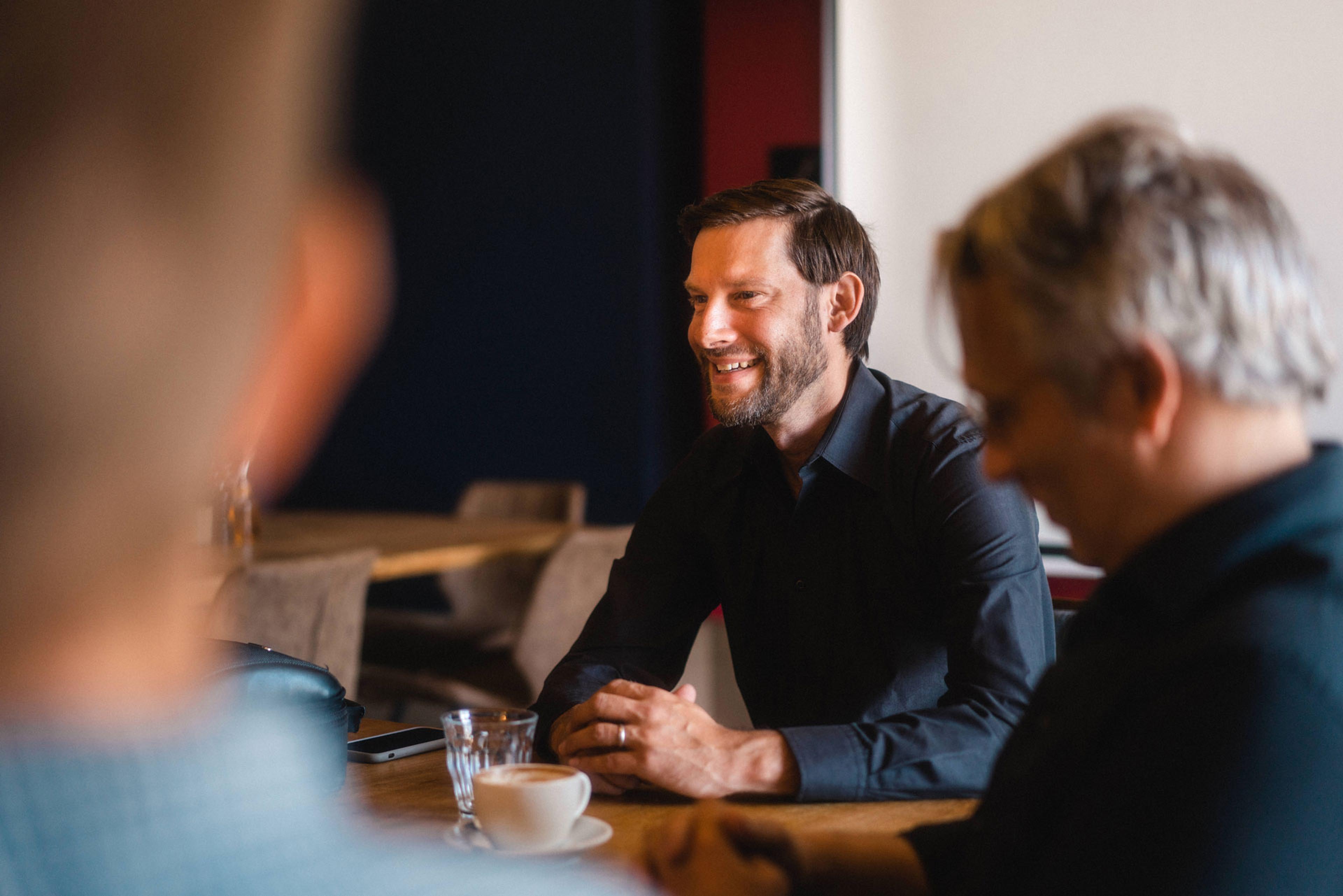Ein Mann in schwarzem Hemd am Tisch mit Kaffeetasse: Bjoern, CEO von 7fridays.