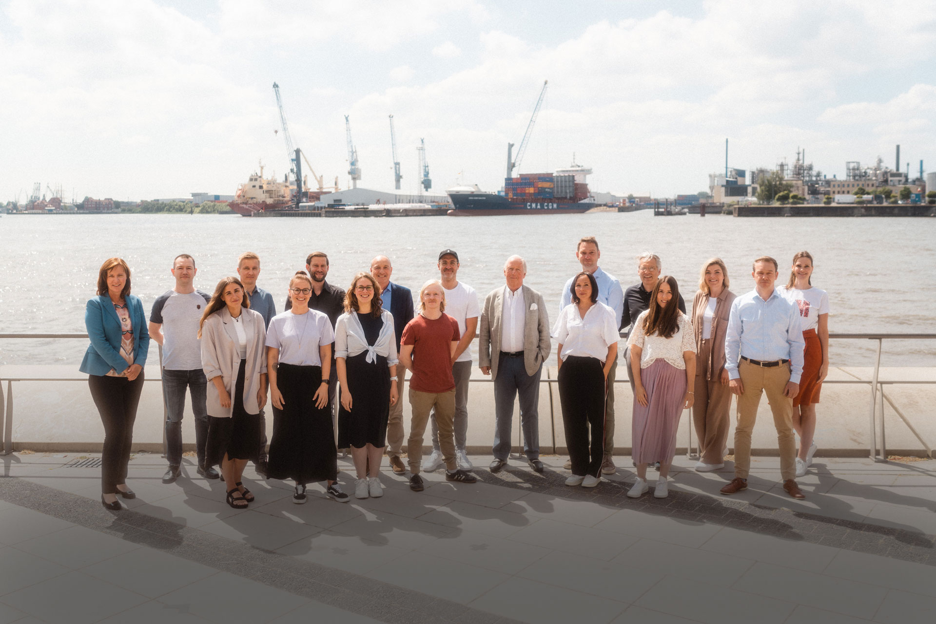Das 7fridays-Team vor dem Hamburger Hafen im Sonnenschein.