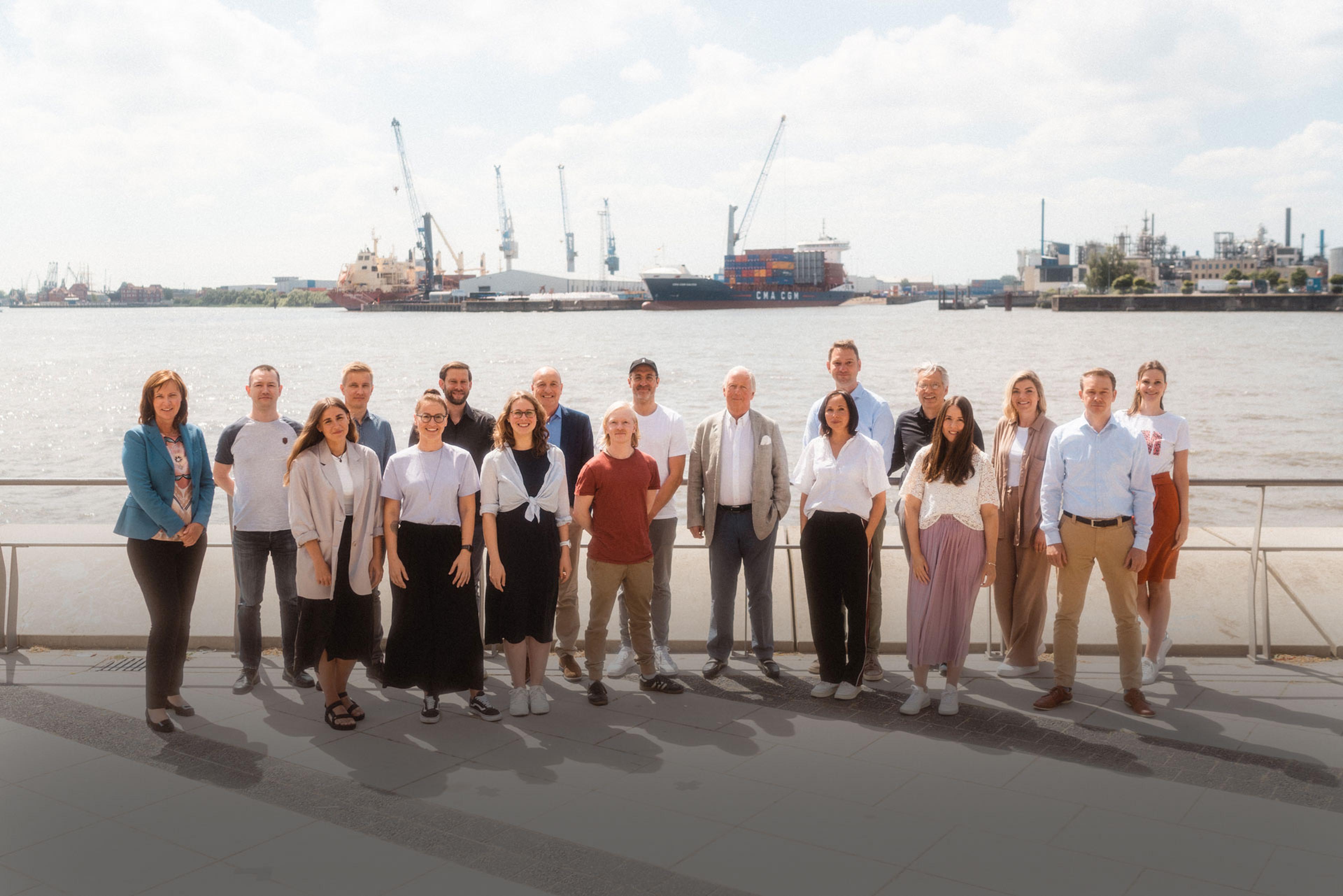 Das 7fridays-Team vor dem Hamburger Hafen im Sonnenschein.