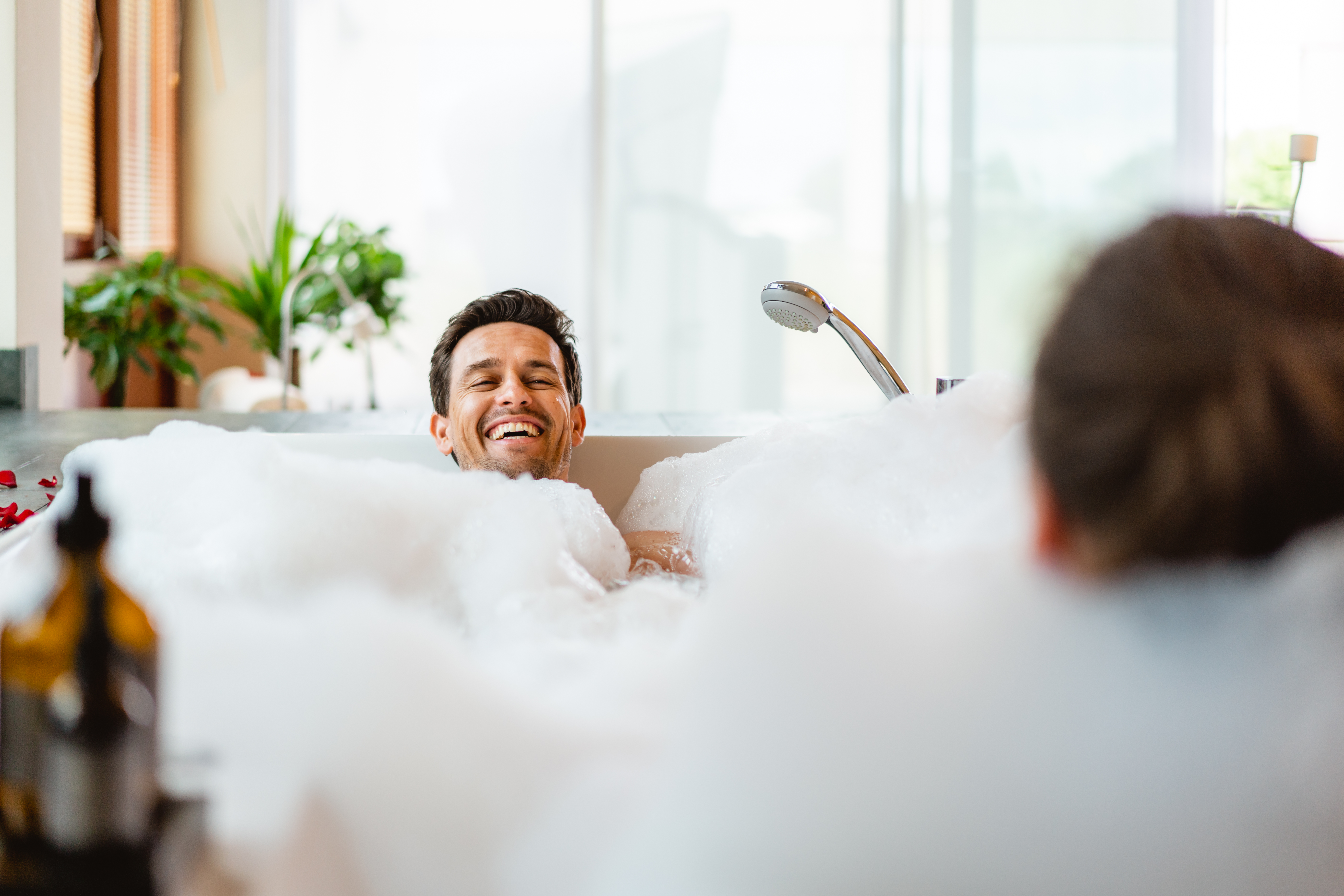 Mann sitzt und lacht in der Badewanne