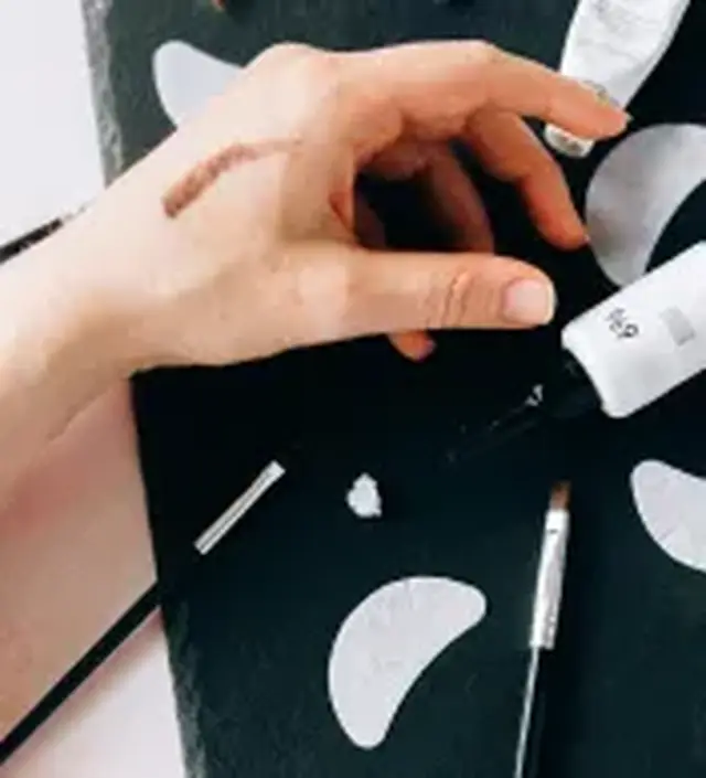 a hand surrounded by makeup brushes