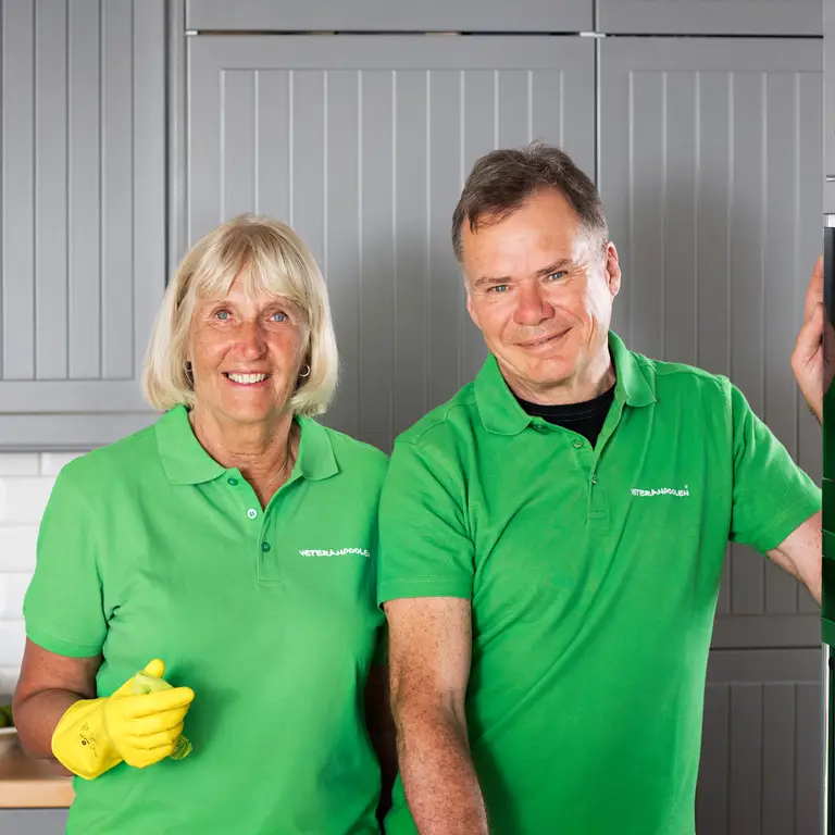 En kvinnlig och en manlig jobbonär står i ett kök bredvid varandra, de har gula gummihandskar och ska städa.