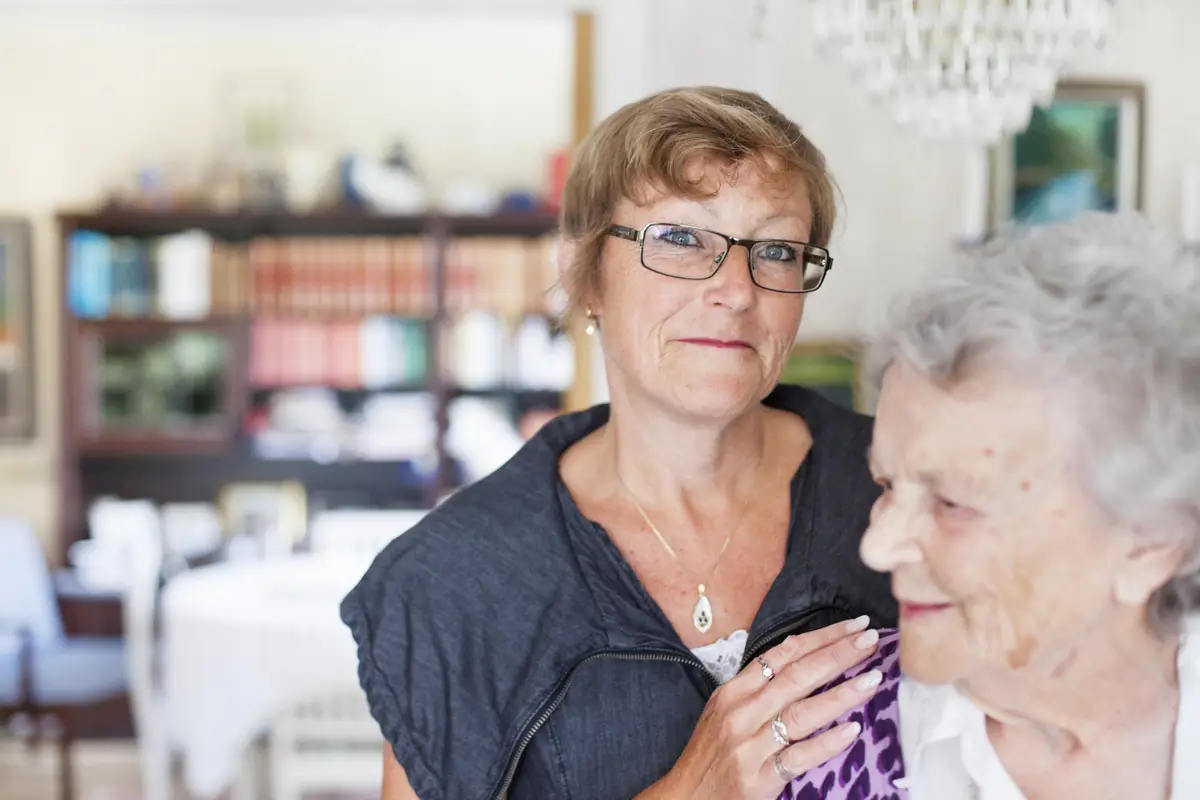 Yngre pensionär håller om äldre pensionär