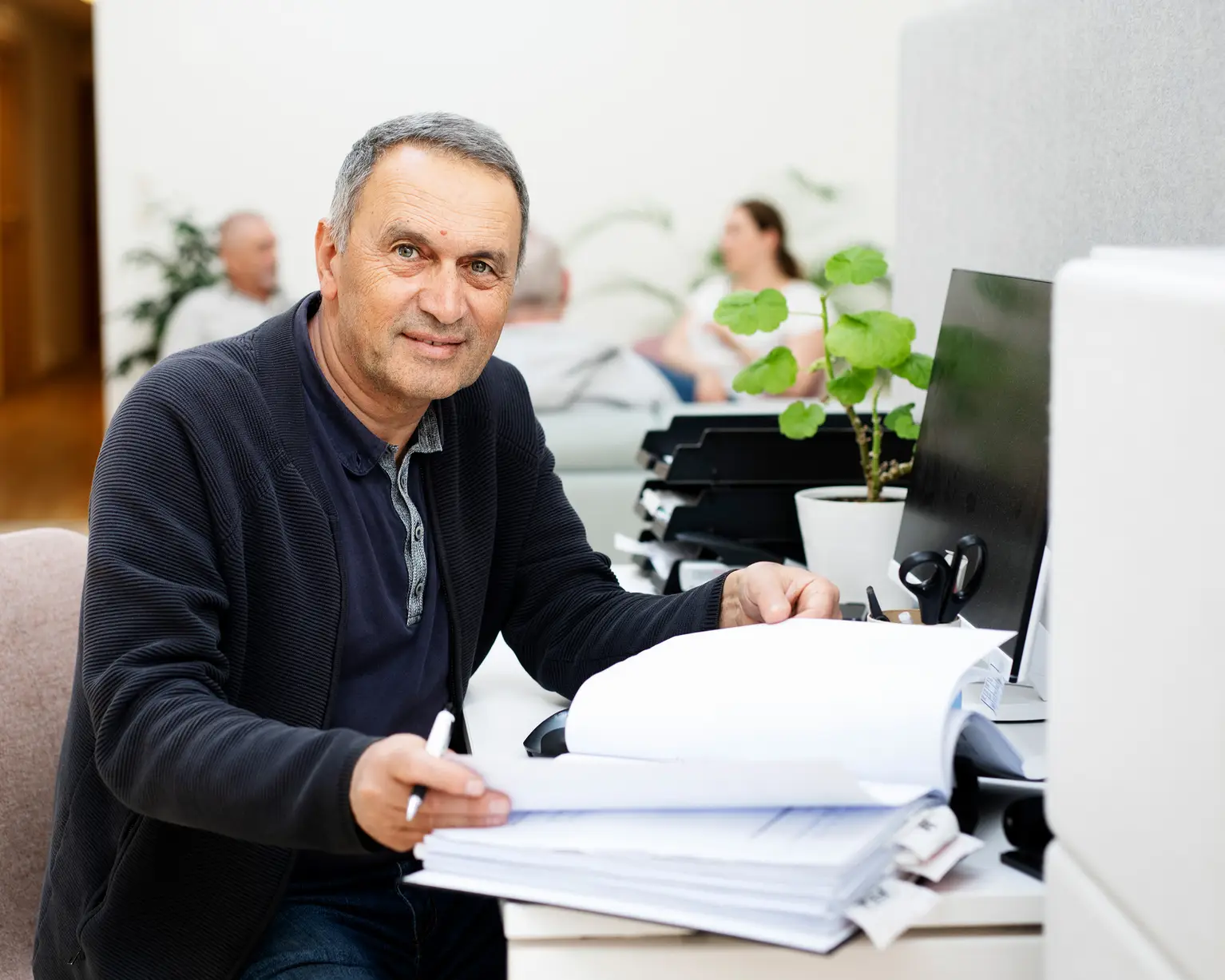 En äldre man sitter med en pärm på ett kontor