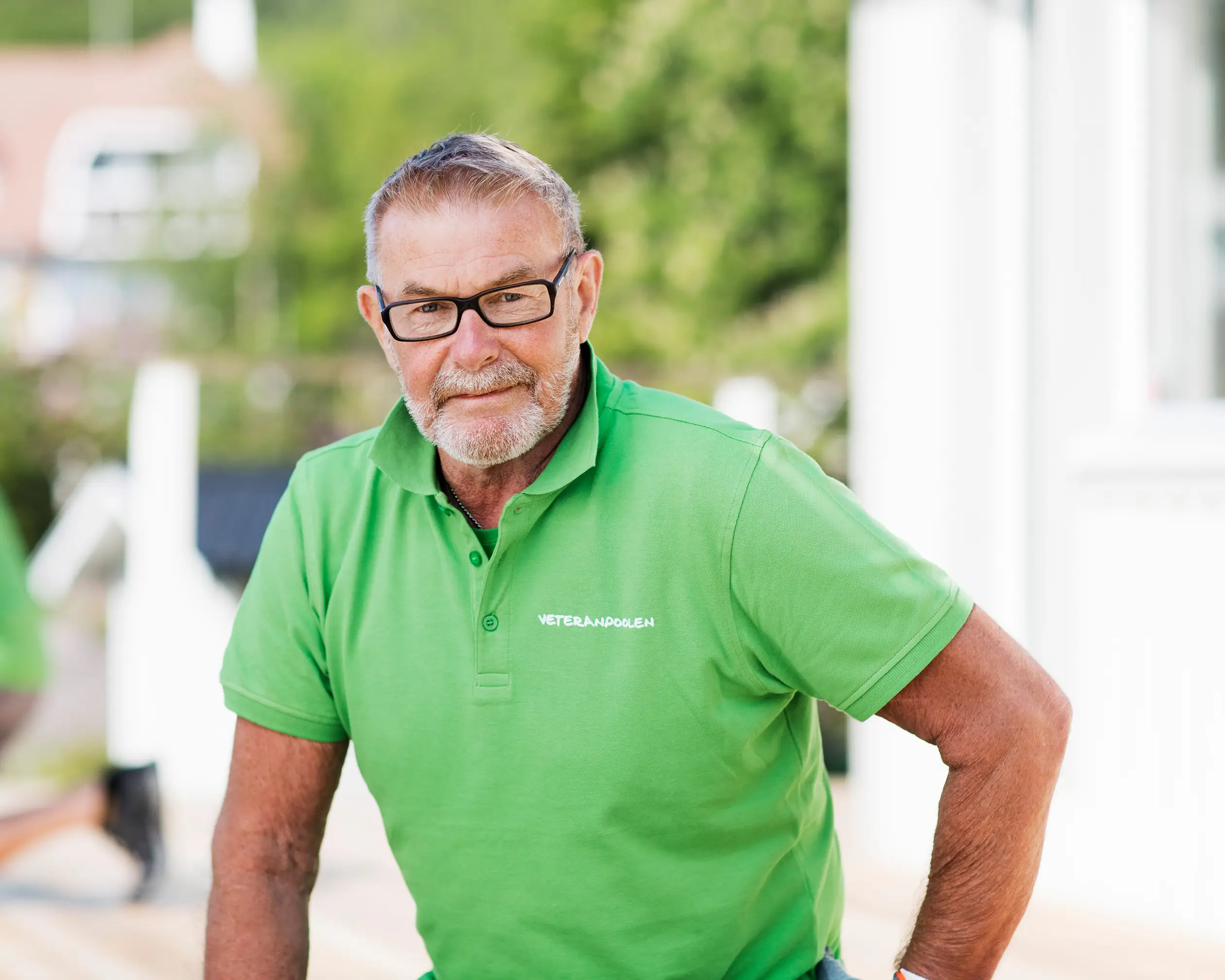 En manlig jobbonär står utomhus,  han har en grön tröja på sig