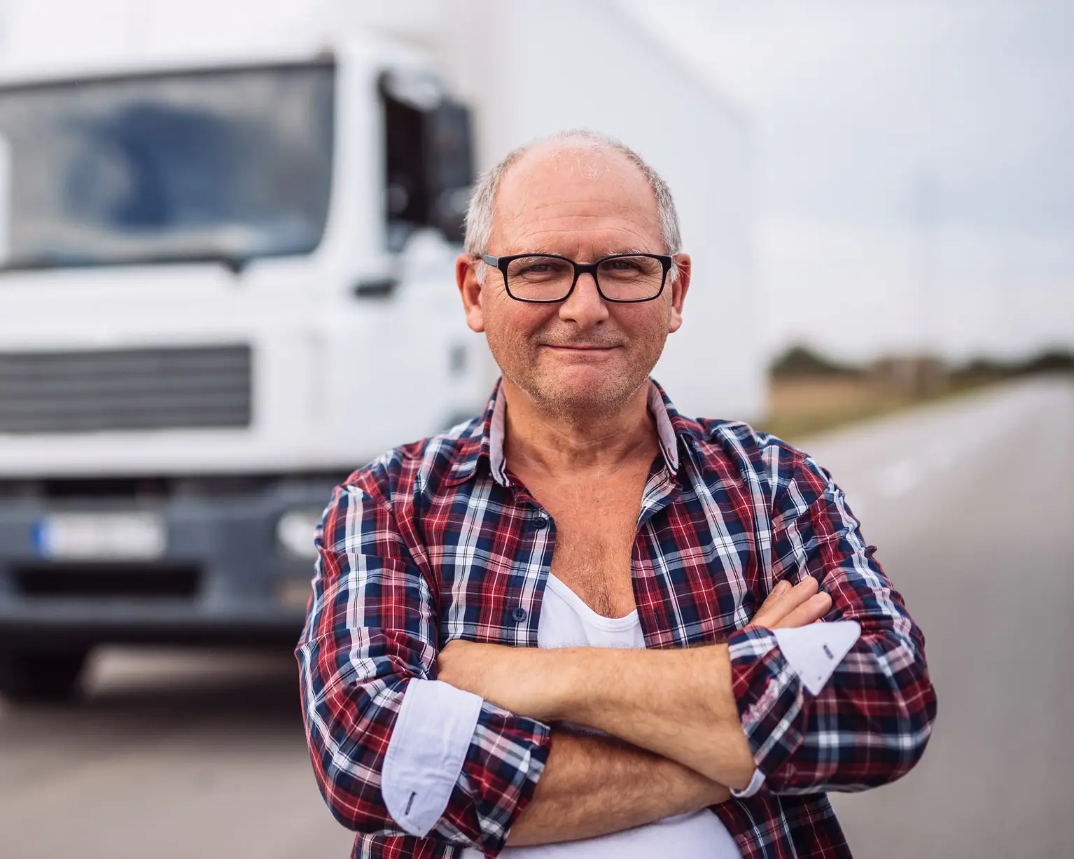 Manlig chaufför står framför en lastbil