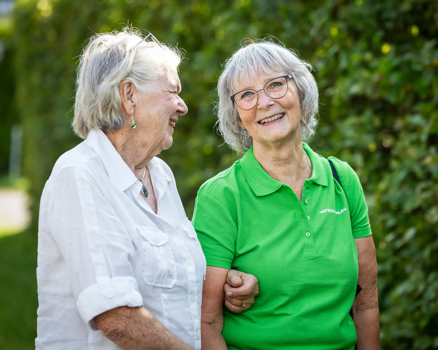 Två äldre kvinnor går en promenad, det ser somrigt ut.