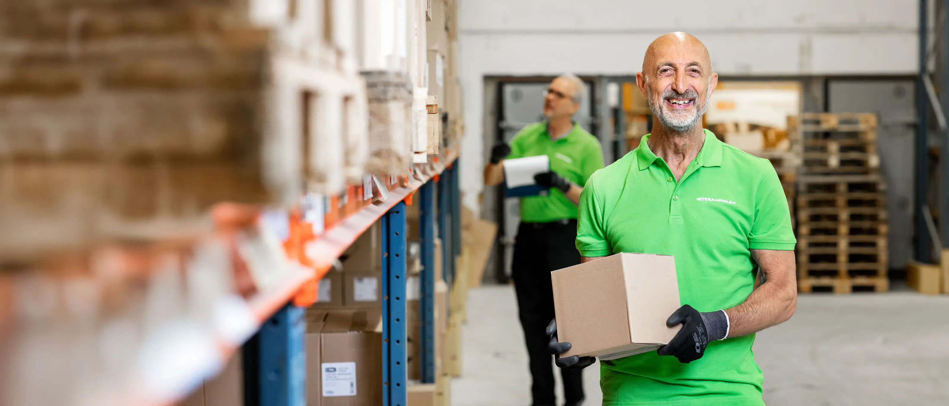 En manlig jobbonär står i ett lager, han håller i en låda