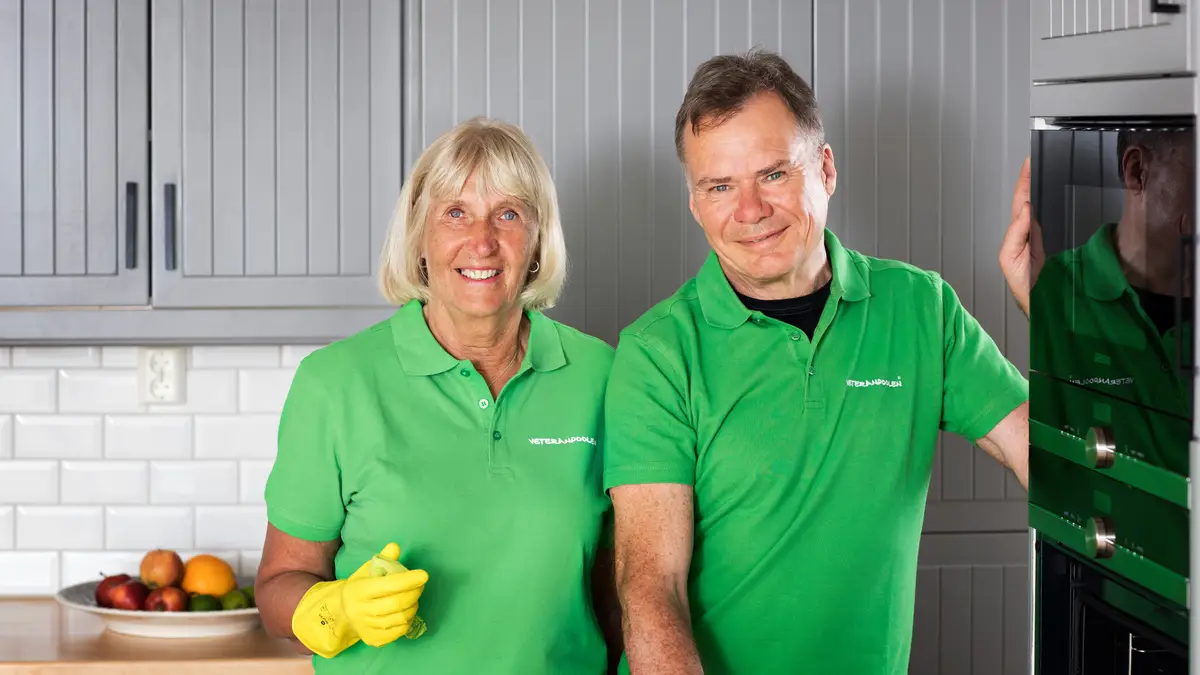 En kvinnlig och en manlig jobbonär står i ett kök bredvid varandra, de har gula gummihandskar och ska städa.