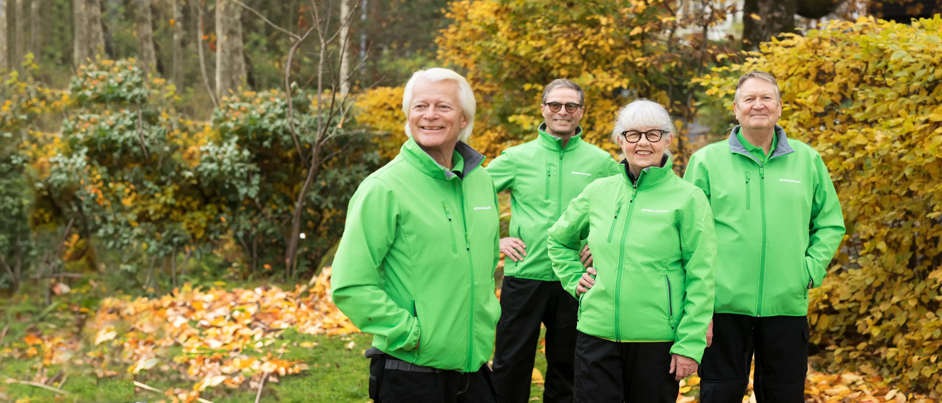 Jobbonärer ute i trädgården i höstväder, tre manliga veteraner och en kvinnlig