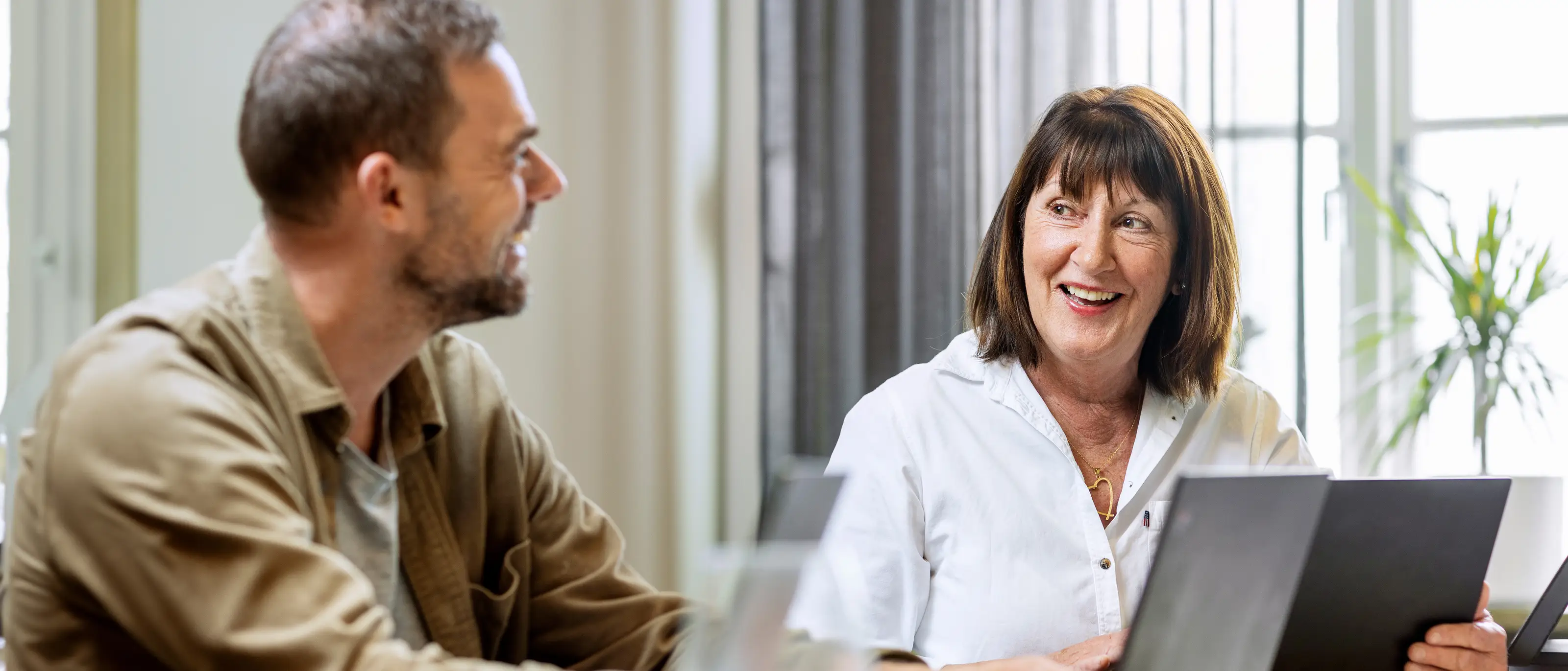 En kvinnlig veteran och en manlig medarbetare har ett möte på ett kontor, de tittar på varandra och ler