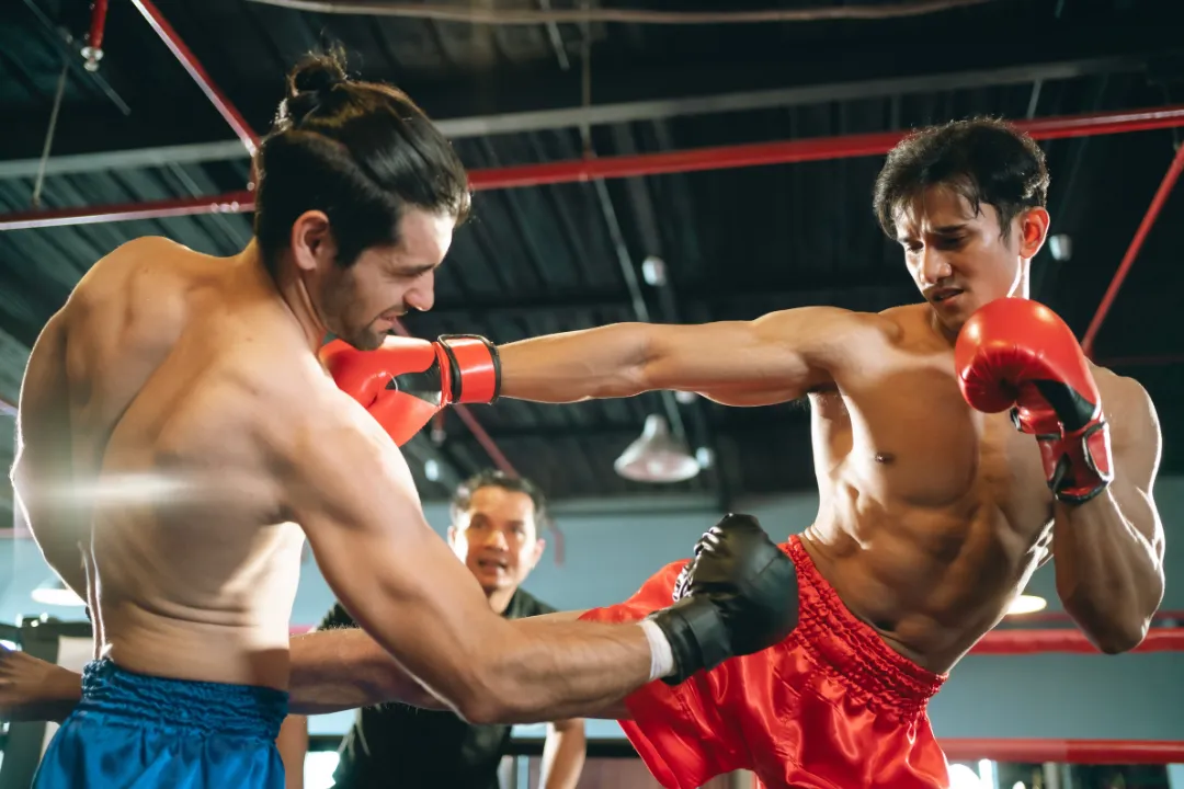 Zwei Männer boxen indoor mit einem Trainer, dieser spart Zeit mit Eversports Manager