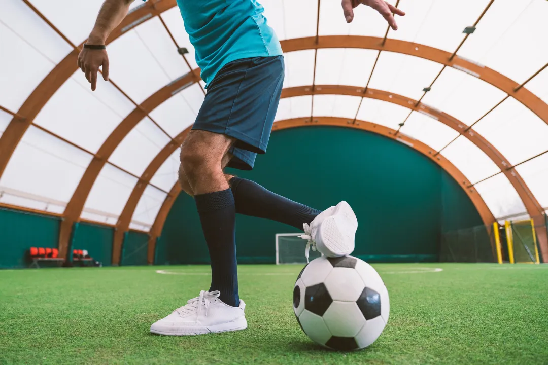 Eine Person spielt mit einem Fußball in einer indoor Halle