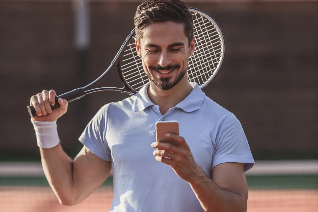 begeisterter Mann bucht die nächste Tennis Session am Handy mit Eversports App