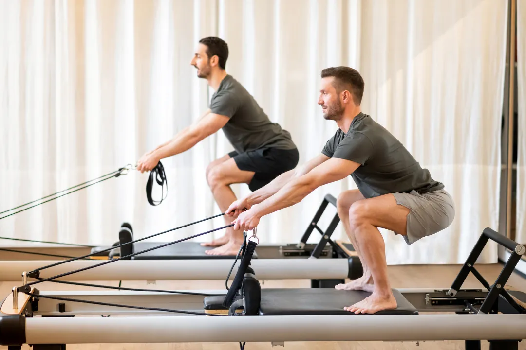 Zwei Männer praktizieren indoor am Reformer Pilates, mit der Eversports Software kann man verschieden Klassen managen