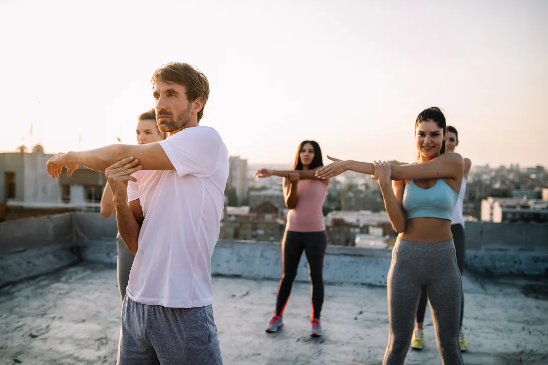 Menschen outdoor beim gemeinsamen Dehnen – zeigt die Verbundenheit und Energie der Eversports Community.
